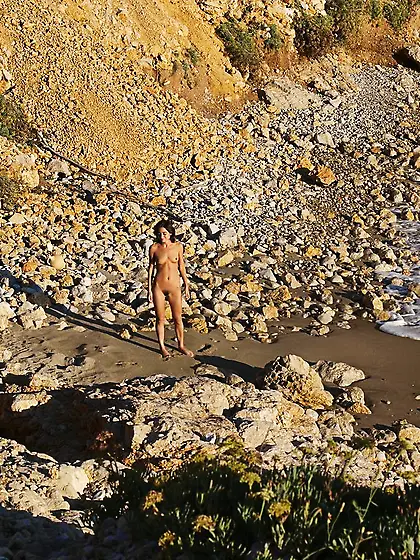 Brunette is ready to do cartwheels while teasing by the water Vi