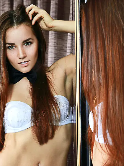 Skirt-wearing brunette wears a bowtie and vacuums the floor on c