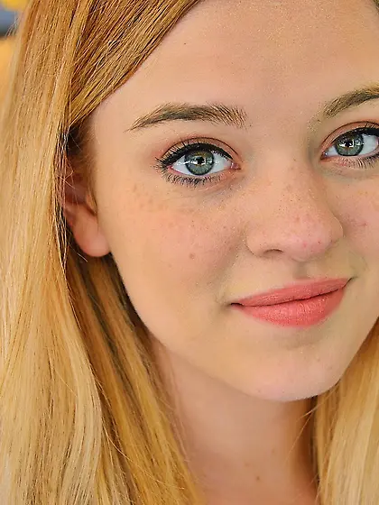 Baby-faced teen shows her pink pussy while posing on the couch