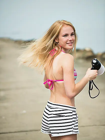 Blond-haired babe with a megaphone strips totally naked on a bea