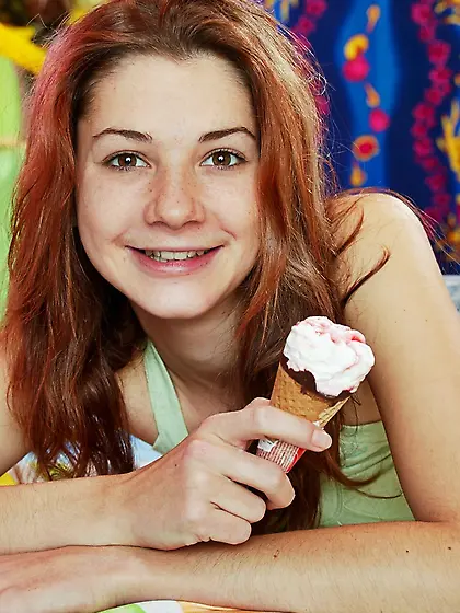 Pleasant girl with red hair eats ice cream and replaces it with