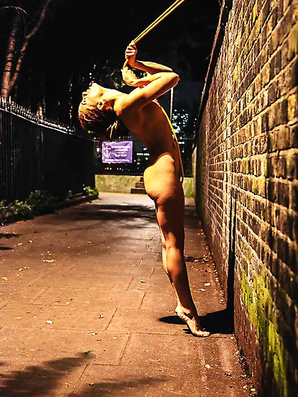 Fit redhead has her arms tied up on the sidewalk.