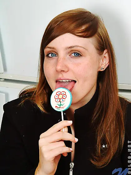 Red haired teen babe Beth Nubiles slowly strips while eating a l