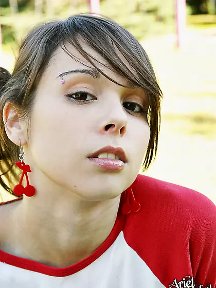 Sporty and sexy Ariel Rebel lies down on a lawn and shows her cl