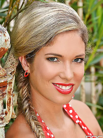 Chick in polka-dot red bodysuit walks in a park stopping on stai