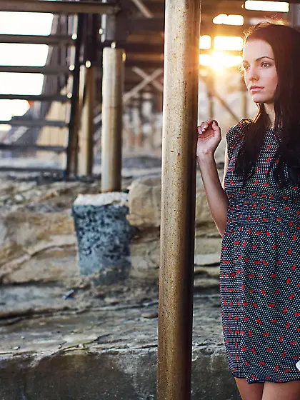 Dress-wearing tanned brunette spreading slender legs on a bed Vi