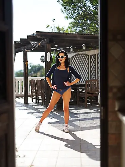 Tempting black-haired bimbo erotically discards clothes to pose