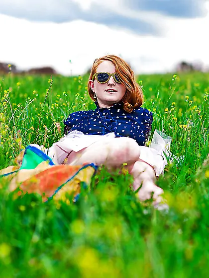 Super-pale ginger lays on the green grass and poses absolutely n