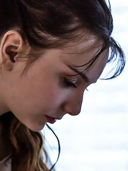 Dark-haired and deeply romantic brunette undressing on a white b