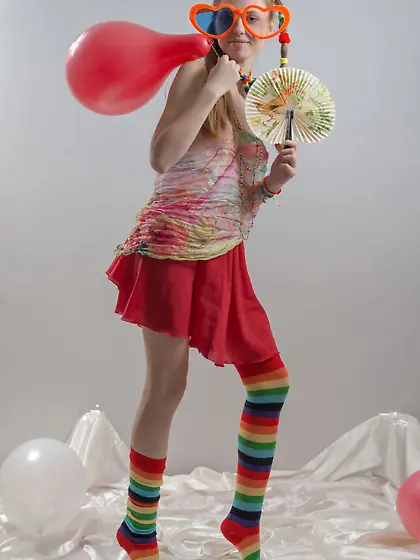 Fancy girl with red balloons and in striped socks bares her smal