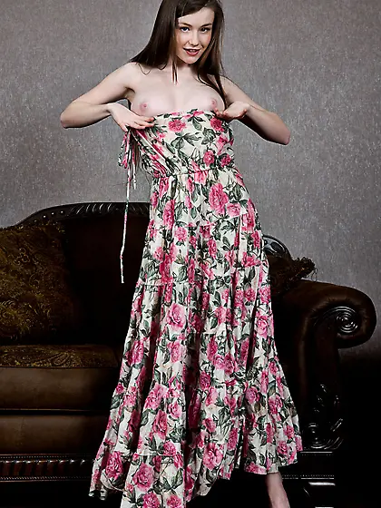 Busty brunette in a long dress teasing her smooth pussy on a sof