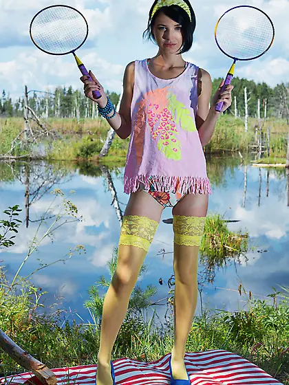 Young woman with black hair waits for partner with two rackets s