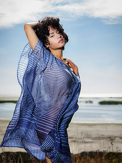 Curly-haired brunette beauty posing in a see-through piece outdo