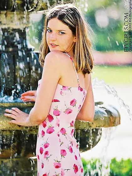 Alicia Angel poses in her flower patterned dress by the fountain