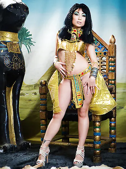 Oriental girl plays the role of Cleopatra posing on a golden thr