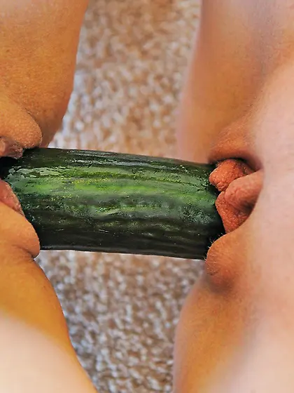 Two girls sharing a cucumber as if it's a double-sided dild