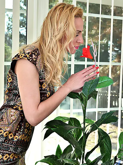 Stunning beauty smells a flower and shows off her pink one betwe