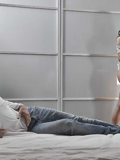 Tanned hottie with wavy hair enjoying hardcore sex on a big bed