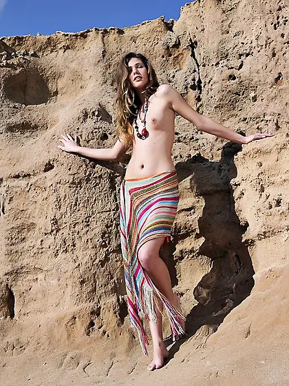 Long-legged lady goes on all fours and shows her ass in the sand